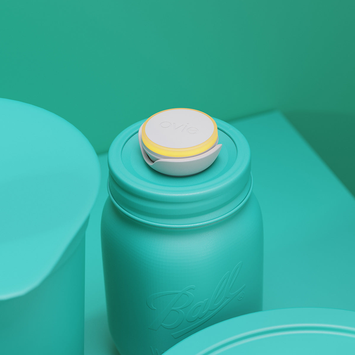 Stylized hero image of Ovie LightTag with light ring lit yellow on top of a mason jar. Entire scene with table top and wall are teal except for product.