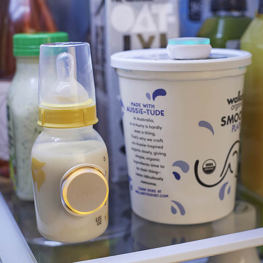 Photo of baby bottle and yogurt container on shelf in fridge with Ovie LightTags on them