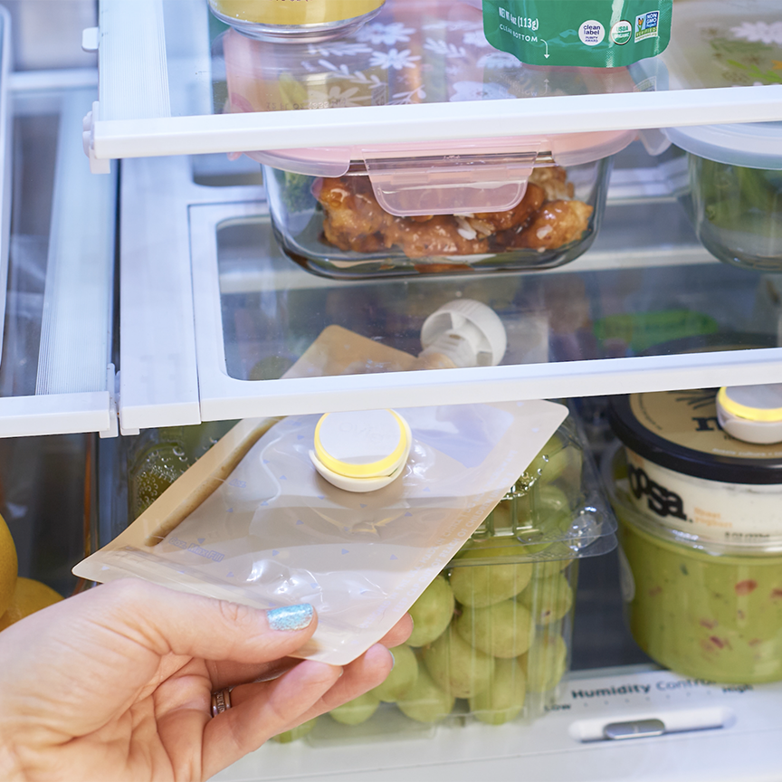 Woman grabbing baby food pouch out of fridge. Pouch has LightTag lit up yellow next to yogurt container with LightTag lit yellow