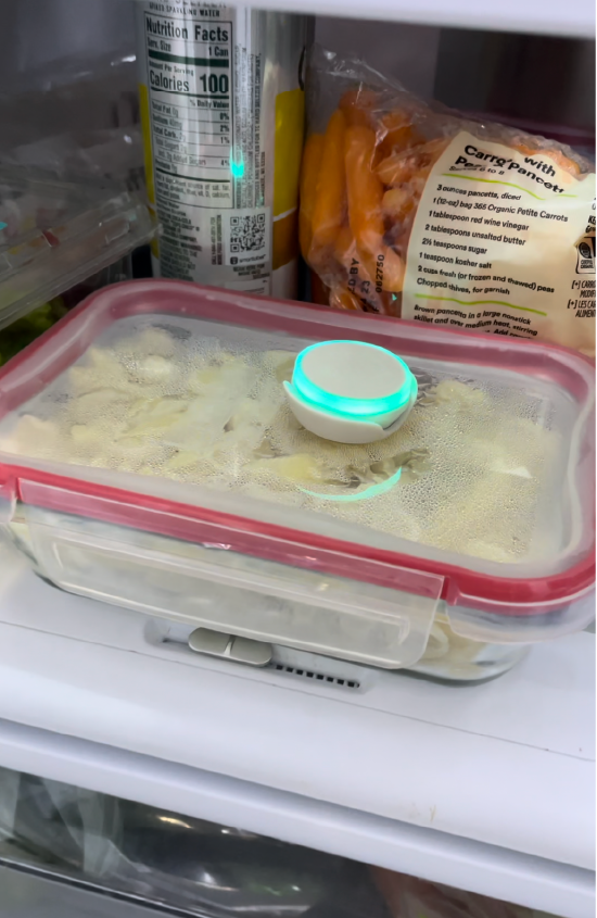 Photo of food clear storage container with pasta inside that has Ovie LightTag on top lit up teal