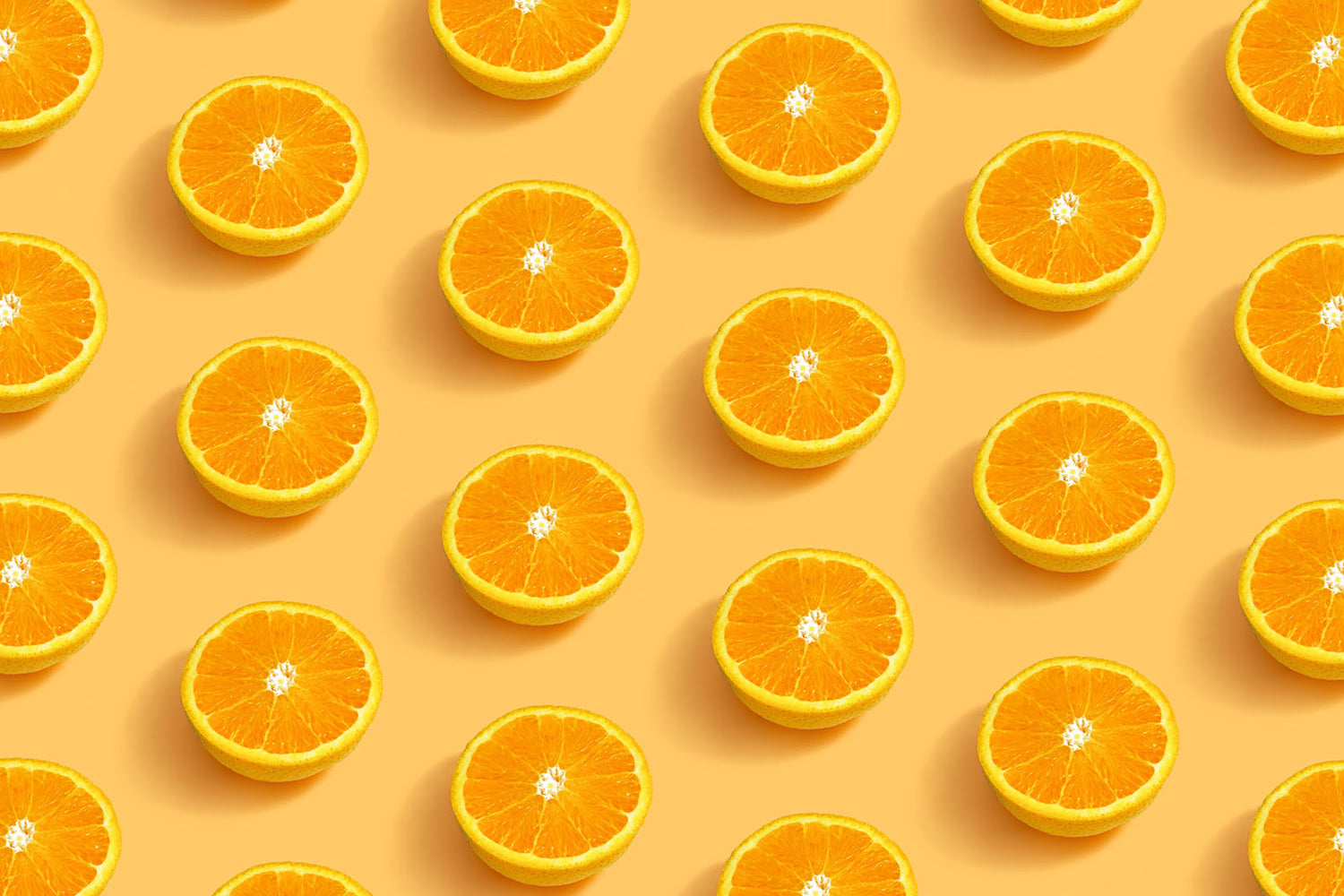 Bright and fun image from above showing pattern of sliced oranges on light orange background