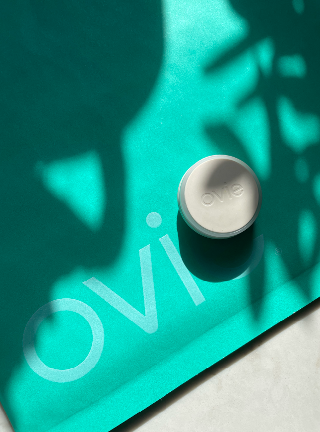 Sunlit photo of Ovie LightTag and teal envelope with Ovie logo on it sitting on a marble counter 