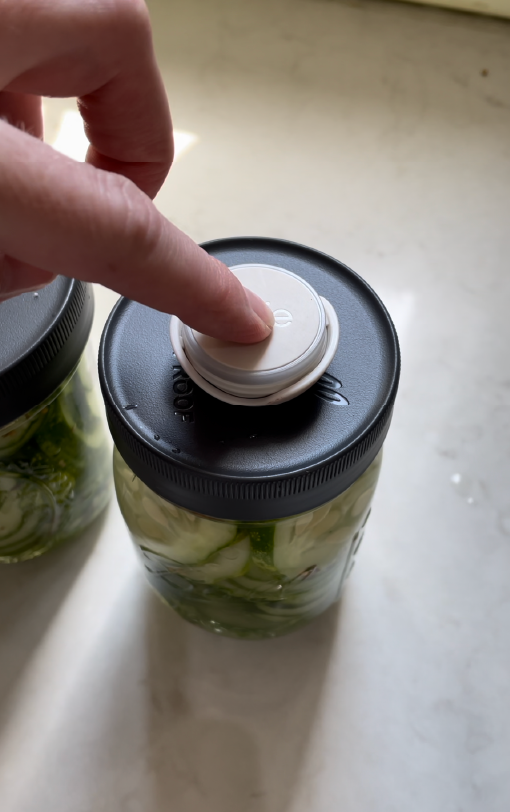 Photo of person pushing Ovie LightTag button that is attached to the top of a homemade pickle jar