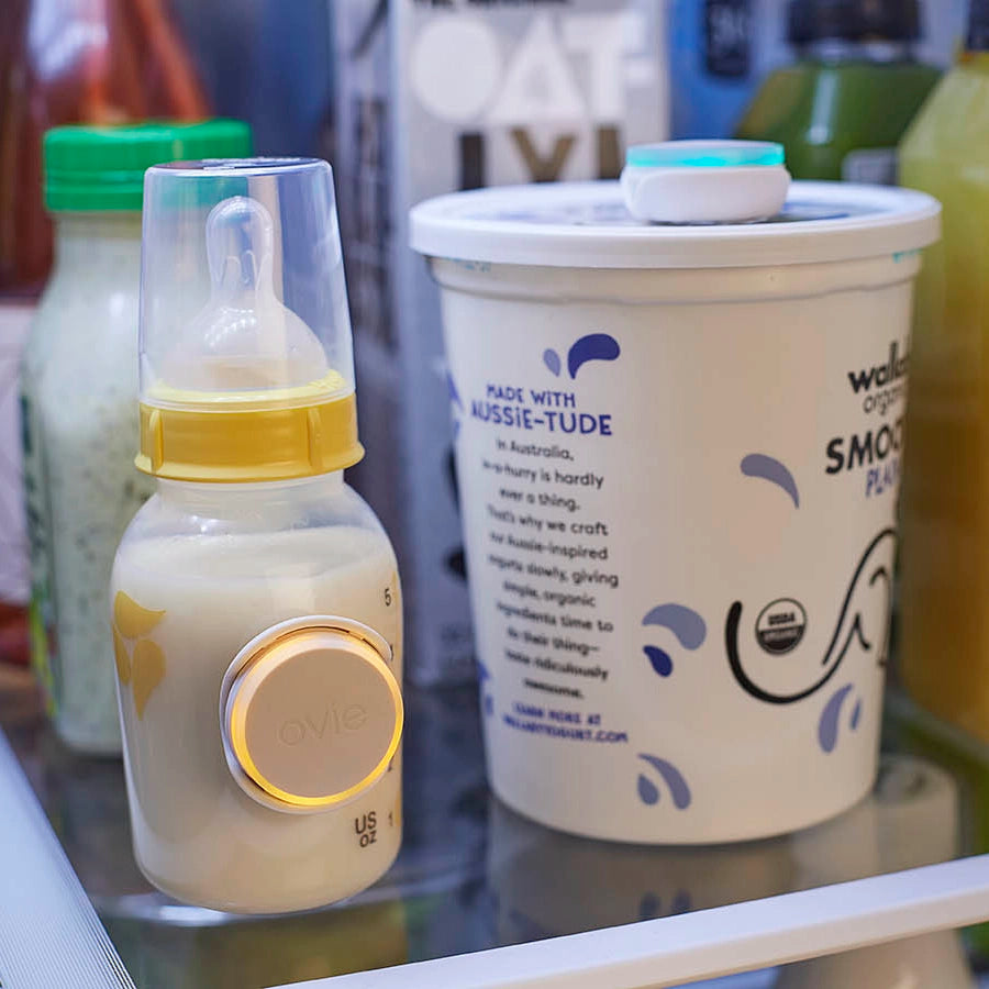 Photo of baby bottle and yogurt container on shelf in fridge with Ovie LightTags on them
