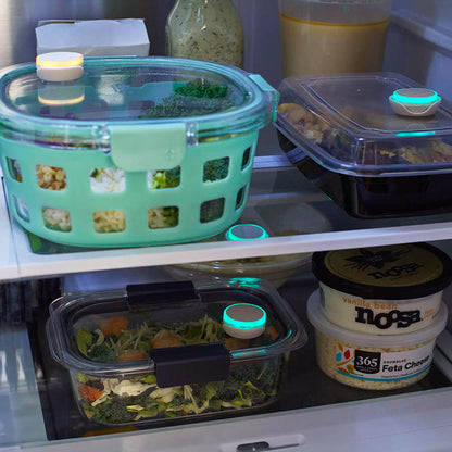 Photo of food containers in fridge with Ovie LightTags on some. One is lit yellow