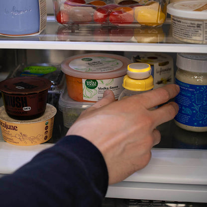 Photo of man reaching into fridge and grabbing bottle of breatmilk with Ovie LightTag on top that it lit up yellow