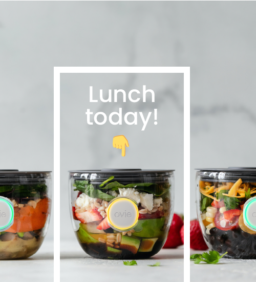 Image of 3 food prep containers on marble background and graphic over the middle one with an emoji finger pointing to the one with the lit up yellow Ovie LightTag and the words "Lunch today!"