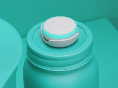 Stylized mostly-teal image focused on jar with Ovie LightTag on top lit up teal
